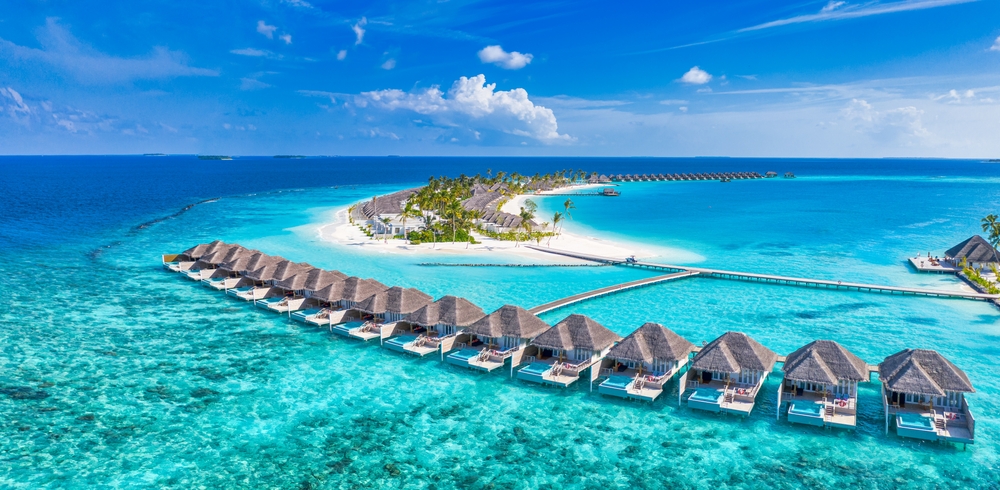 Aerial view of Maldives overwater villas and turquoise lagoon with tropical island