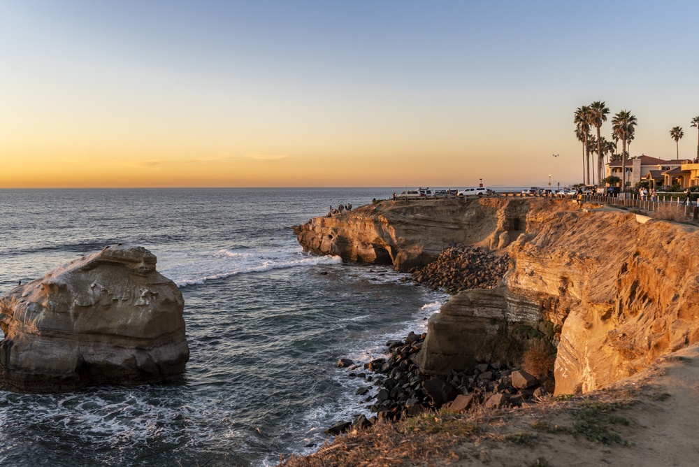 San Diego coastline cliffs at sunset with palm trees and ocean waves