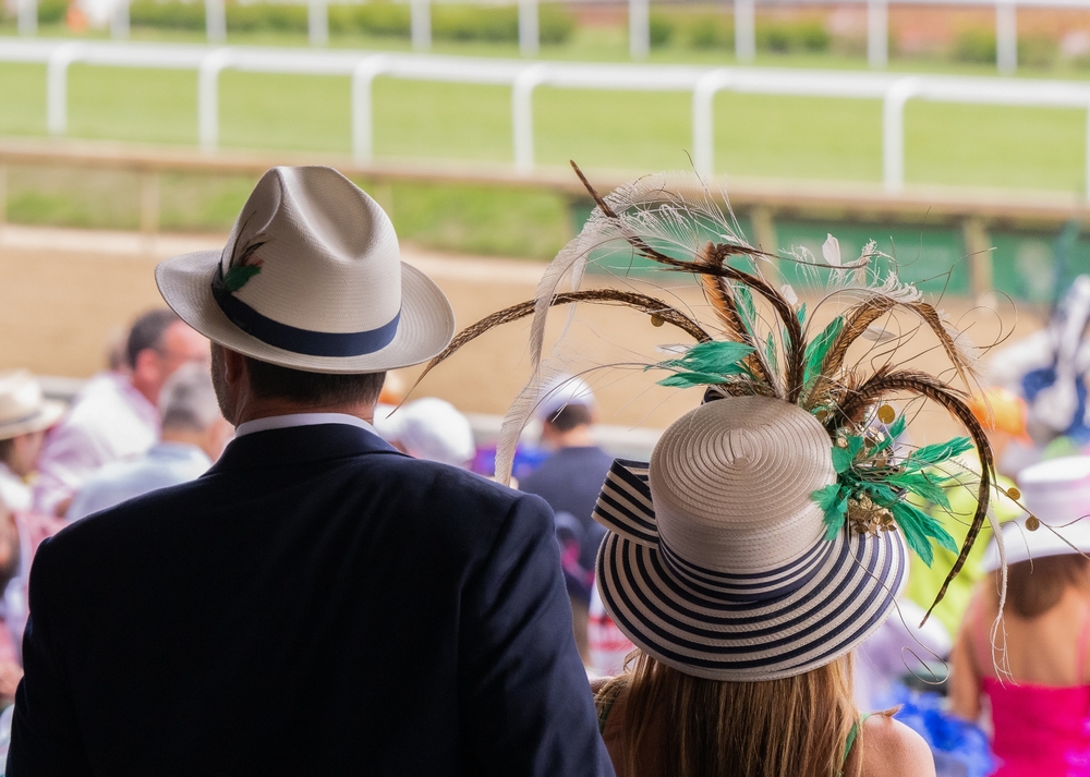 Elegantly dressed spectators in derby hats watching horse racing at Churchill Downs