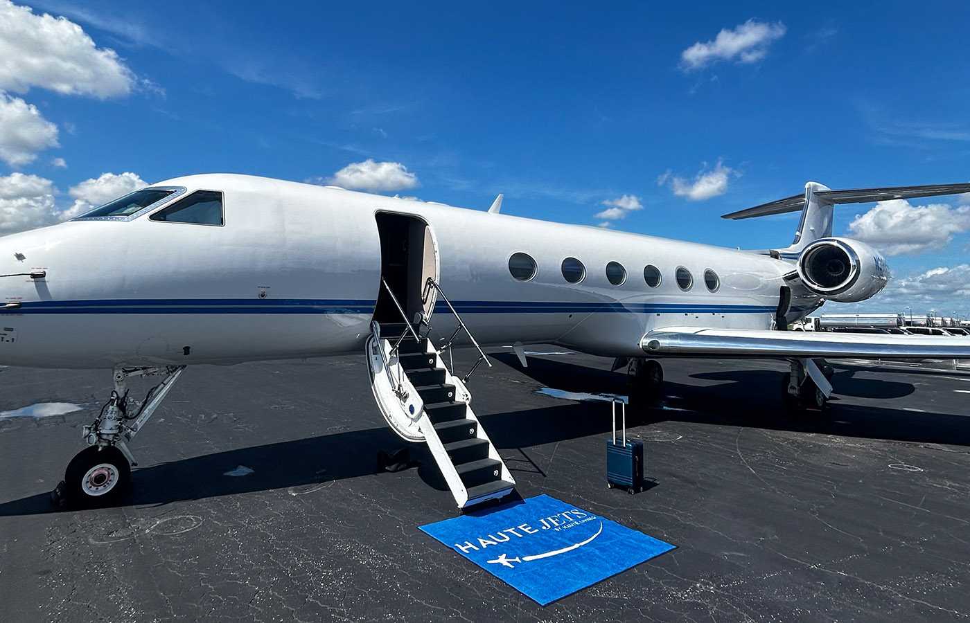 Haute Jets Gulfstream private jet on the tarmac with airstairs deployed and branded carpet